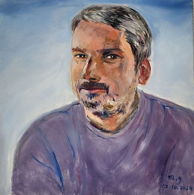 Portrait d'un homme avec des cheveux grisonnants, portant un pull violet et souriant.
